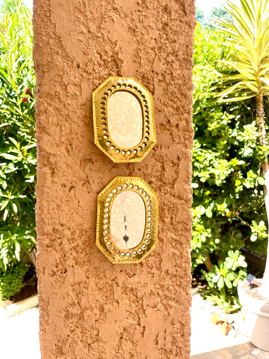 Duo de miroirs octogonaux en laiton doré sur un mur